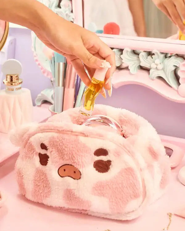 A person puts makeup into a pink plush Valentine puffy makeup pouch with a decorative background.